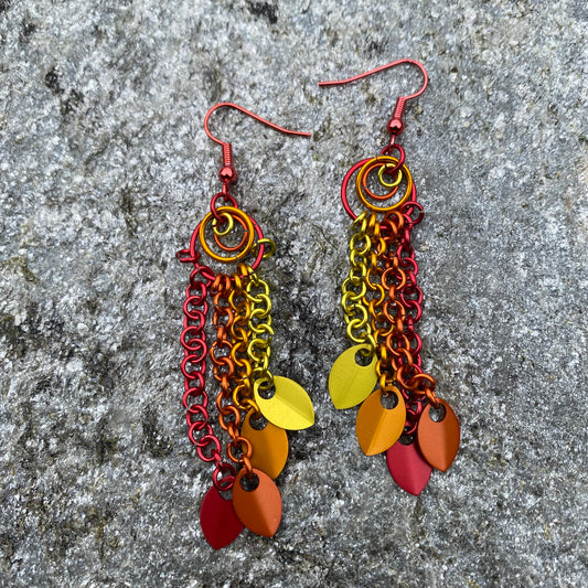 Colorful anodized aluminum jump rings in red, orange and yellow with whimsical aluminum leaf charms suspended from red niobium ear wires.